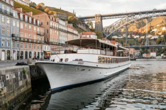 Bateau de croisière amarré sur le Douro à Porto avec le pont Dom Luís I en arrière-plan en automne