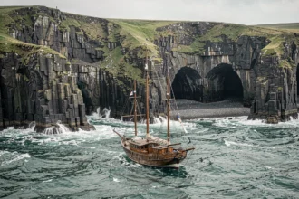 Voilier ancré face aux falaises sauvages de la côte irlandaise avec des vagues de l'Atlantique